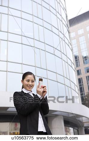 Stock Photography - Business young woman looking at cell phone, smiling. Fotosearch