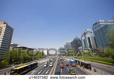 Stock Image - Traffic on road between buildings. Fotosearch
