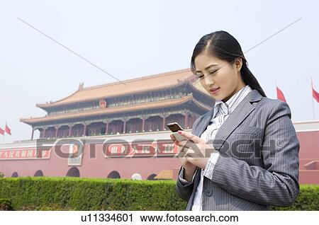 Young woman looking at cell phone before Tiananmen Square View Large Photo Image Stock Image - Young woman looking at cell phone before Tiananmen Square. Fotosearch