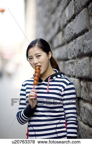 Young woman eating tomatoes on sticks at hutong View Large Photo Image Stock Photo - Young woman eating tomatoes on sticks at hutong. Fotosearch