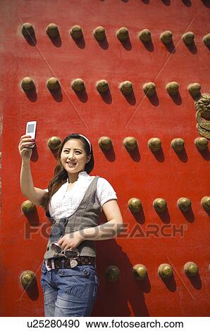 Young woman leaning against gate taking photograph View Large Photo Image Stock Image - Young woman leaning against gate taking photograph. Fotosearch