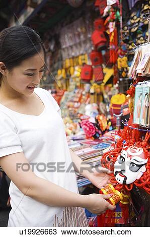Stock Image - Young woman looking at mask. Fotosearch