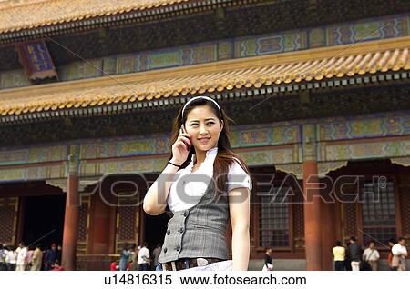 Stock Photography - Young woman on the phone in front of qianqinggong. Fotosearch