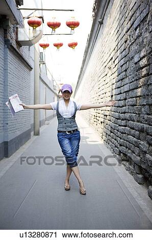 Young woman outstretching her arms in hutong View Large Photo Image Stock Image - Young woman outstretching her arms in hutong. Fotosearch