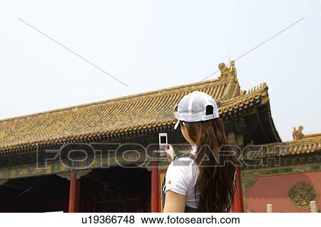 Stock Photo - Young woman taking photograph at Forbidden City. Fotosearch