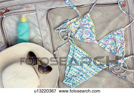 Stock Photo - Bikini, sunglasses, and hat on a suitcase. Fotosearch
