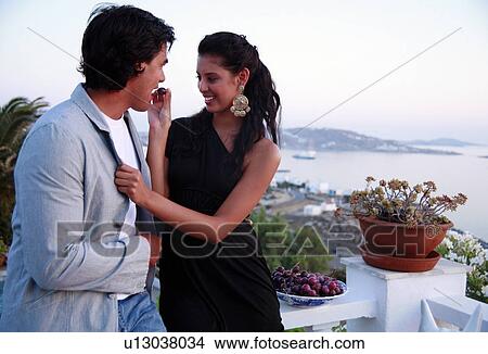 Picture - Couple eating grapes on balcony. Fotosearch