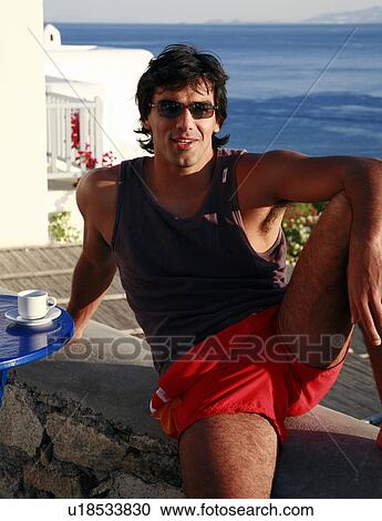 Young man sitting on balcony with a view View Large Photo Image Stock Image - Young man sitting on balcony with a view. Fotosearch