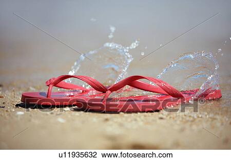 Stock Image - Flip flops on the beach with water splashing. Fotosearch