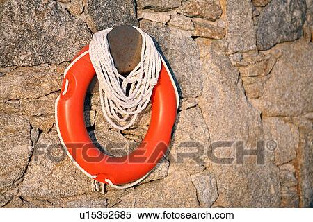 Stock Photography - Life preserver on stone wall. Fotosearch
