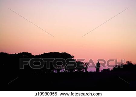 Stock Photography - Silhouette of person standing in sunset landscape. Fotosearch