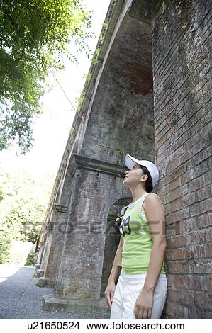 A young woman standing against brick wall View Large Photo Image Picture - A young woman standing against brick wall. Fotosearch