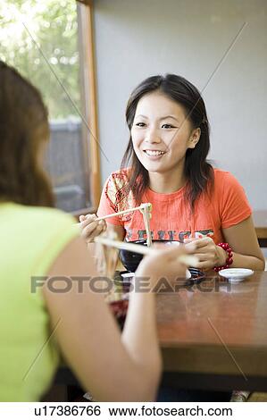 Stock Photograph - Two young women eating noodles. Fotosearch