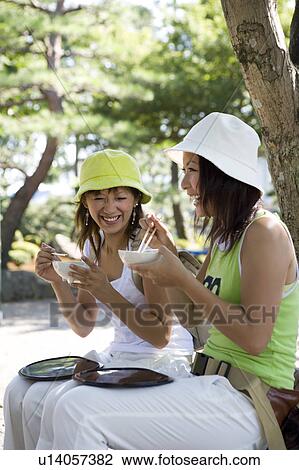Stock Image - Two young women eating traditional Japanese desserts. Fotosearch