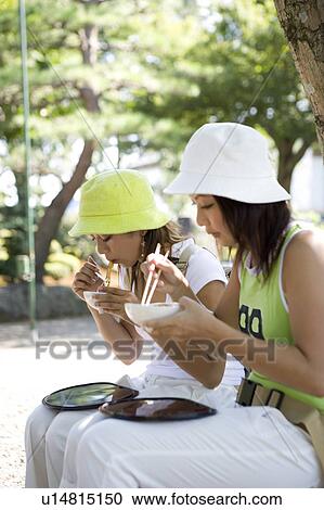 Stock Image - Two young women eating traditional Japanese desserts. Fotosearch