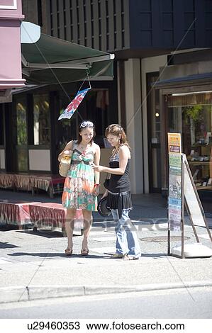 Stock Image - Two young women looking at mobile phone. Fotosearch
