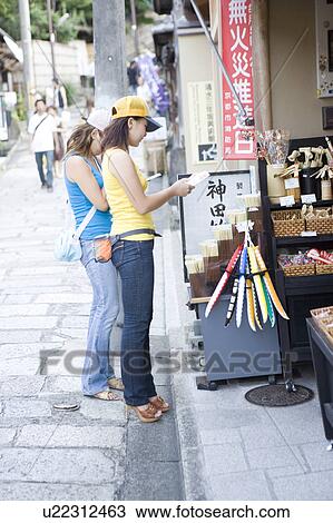 Stock Image - Two young women looking souvenir shop in Kyoto, Japan. Fotosearch
