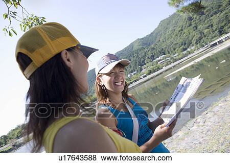 Two young women reading guidebook View Large Photo Image Stock Photo - Two young women reading guidebook. Fotosearch