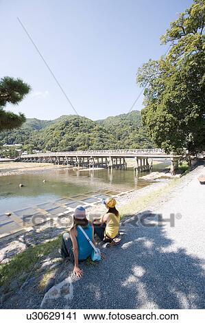 Stock Image - Two young women sitting in Arashiyama, Kyoto, Japan. Fotosearch