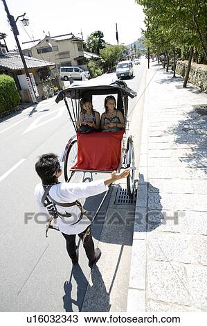 Stock Image - Two young women sitting in rickshaw. Fotosearch