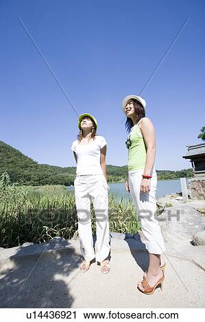 Stock Image - Two young women standing by Hirosawa Pond, Kyoto, Japan. Fotosearch