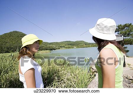 Stock Image - Two young women standing by Hirosawa Pond, Kyoto, Japan. Fotosearch