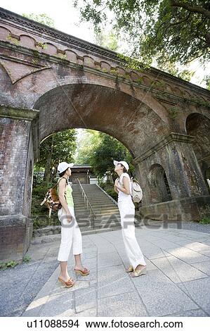 Two young women standing under bridge View Large Photo Image Picture - Two young women standing under bridge. Fotosearch