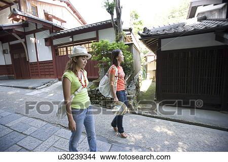 Two young women walking in old town View Large Photo Image Picture - Two young women walking in old town. Fotosearch