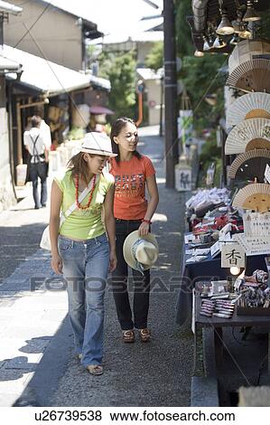 Two young women walking in old town View Large Photo Image Stock Photo - Two young women walking in old town. Fotosearch