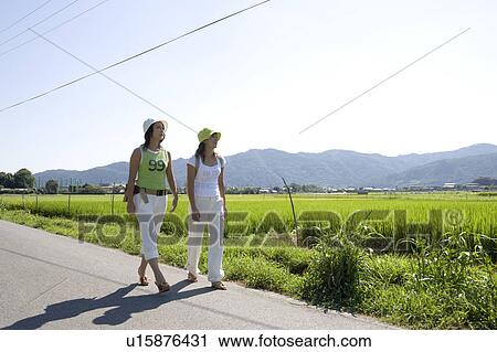 Two young women walking on rural road View Large Photo Image Stock Image - Two young women walking on rural road. Fotosearch