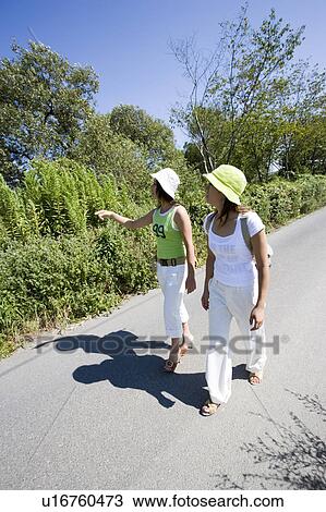 Two young women walking on rural road View Large Photo Image Stock Image - Two young women walking on rural road. Fotosearch