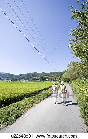 Two young women walking on rural road View Large Photo Image Stock Image - Two young women walking on rural road. Fotosearch