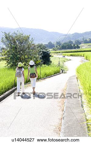 Stock Photo - Two young women walking on rural road. Fotosearch