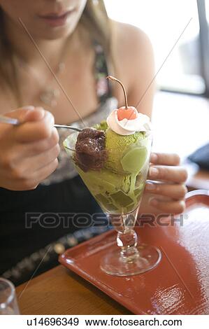 Stock Photo - Young woman eating green tea ice cream. Fotosearch