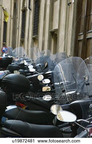 Stock Image - Row of motorcycles beside building, Italy.. Fotosearch