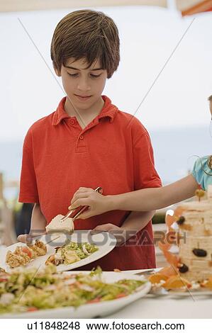 Boy being served by girl at buffet View Large Photo Image Stock Photo - Boy being served by girl at buffet. Fotosearch