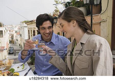 Stock Photo - Couple toasting at a table with Greek food. Fotosearch