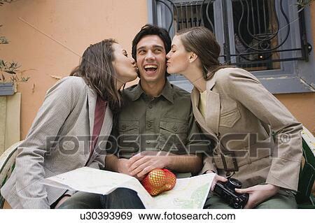 Man on bench being kissed by two women View Large Photo Image Stock Photo - Man on bench being kissed by two women. Fotosearch