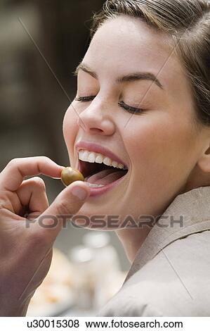 Stock Photo - Man's hand feeding woman an olive. Fotosearch