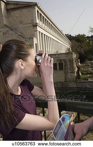 Stock Image - Woman with binoculars at archaeological site. Fotosearch