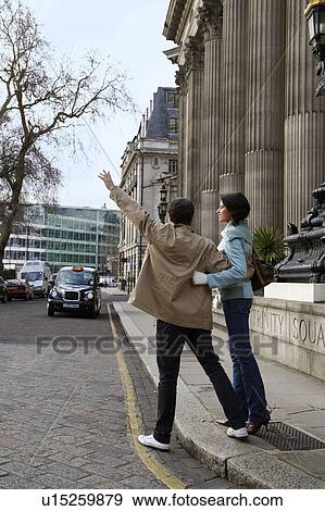 Stock Photo - Couple hailing London Taxi. Fotosearch