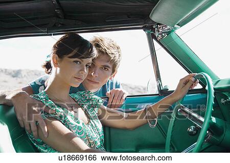 Stock Photograph - Man leaning into car holding woman.. Fotosearch