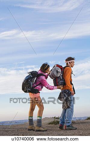 Stock Photograph - Woman adjusting man's backpack.. Fotosearch