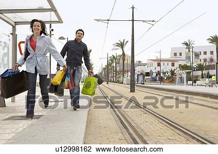 Young couple carrying shopping running to tram stop View Large Photo Image Stock Image - Young couple carrying shopping running to tram stop. Fotosearch