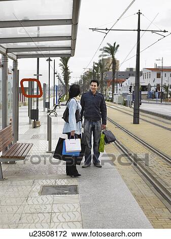 Young couple holding shopping standing at tram stop View Large Photo Image Stock Image - Young couple holding shopping standing at tram stop. Fotosearch