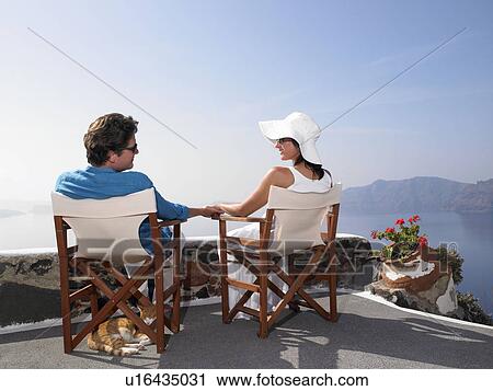 Stock Image - Couple sitting on a sundeck. Fotosearch