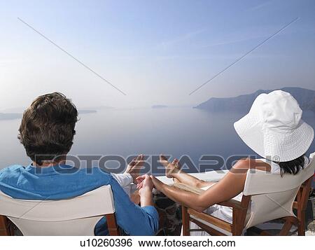 Couple sitting on a sundeck View Large Photo Image Stock Photograph - Couple sitting on a sundeck. Fotosearch