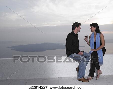 Couple toasting glasses, sea view View Large Photo Image Stock Photo - Couple toasting glasses, sea view. Fotosearch