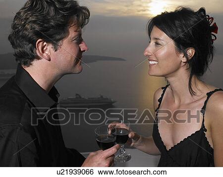 Stock Photograph - Couple toasting glasses, sea view. Fotosearch