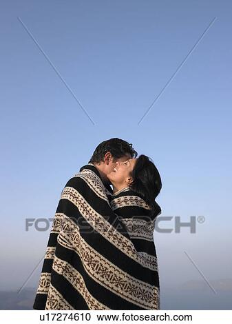 Stock Image - Couple wrapped in a cover, hugging. Fotosearch